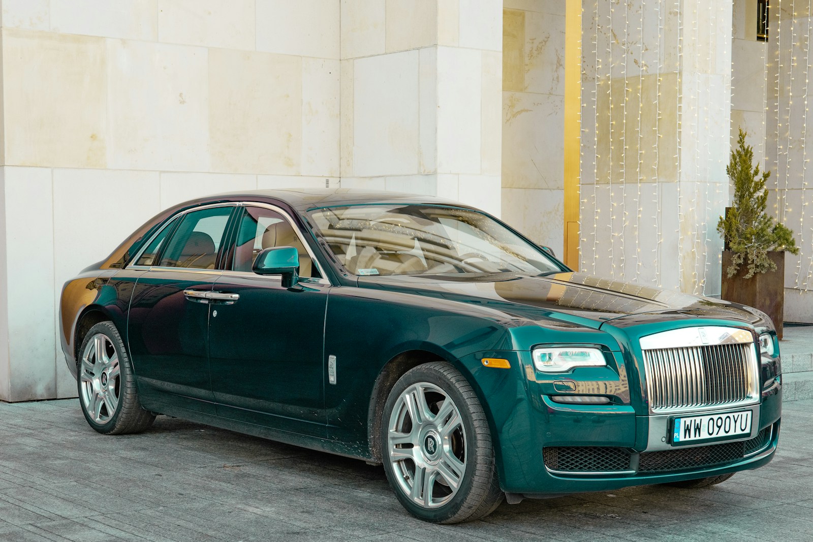 A dark green rolls-royce sedan parked outside.